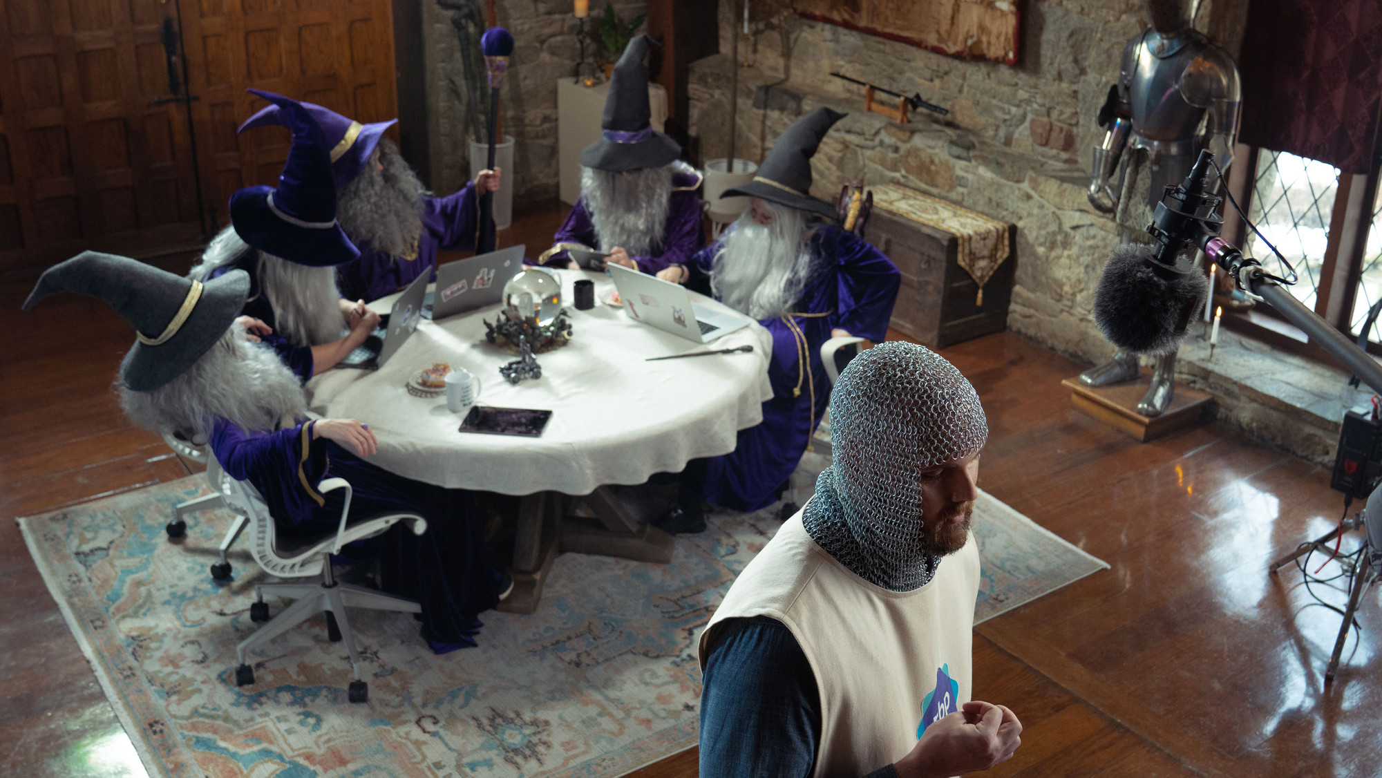 Filming a commercial video scene of wizards sitting around a table with laptops